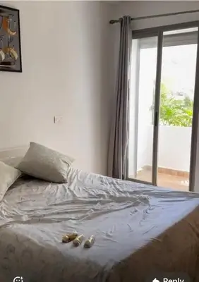 a bed with shoes on it with a window at Apparemment sur mer avec piscine al Mansouria in O Ben Slimane
