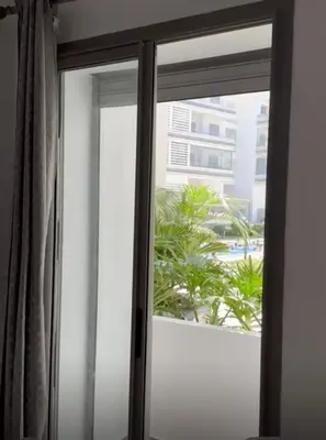 a sliding glass window with a view of a building at Apparemment sur mer avec piscine al Mansouria in O Ben Slimane