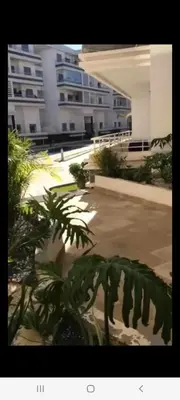 a view of a building with a plant in the foreground at Apparemment sur mer avec piscine al Mansouria in O Ben Slimane