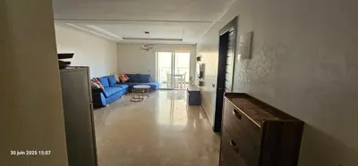 a living room with a blue couch and a table at Appartement tamaris in Sidi Rahal