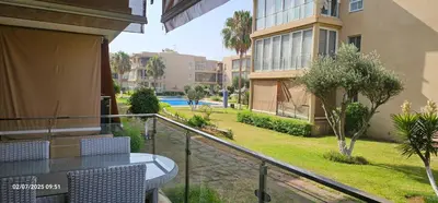 a balcony with a table and chairs and a yard at Appartement tamaris in Sidi Rahal