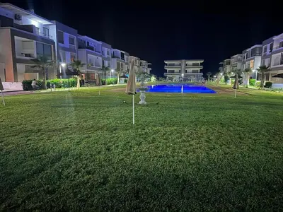 a lawn with an umbrella in the middle of a building at Appartement Balneaire avec piscine à El Mansouria in Mansouria