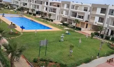 a large yard with a swimming pool in front of a building at Appartement Balneaire avec piscine à El Mansouria in Mansouria