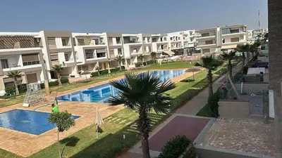 an apartment complex with a swimming pool and palm trees at Appartement Balneaire avec piscine à El Mansouria in Mansouria