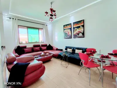 a living room with a couch and red chairs at appartement avec piscines in Mansouria