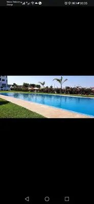 two pictures of a large pool with palm trees in the background at appartement avec piscines in Mansouria