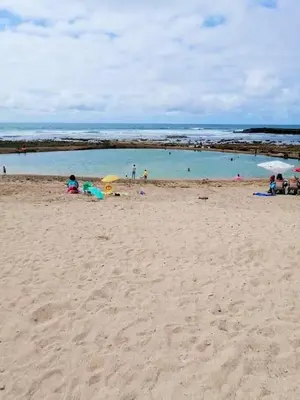 a group of people on a beach with umbrellas at appartement avec piscines in Mansouria