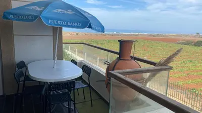 a table and a vase on a balcony with an umbrella at Puerto Banus in Mansouria