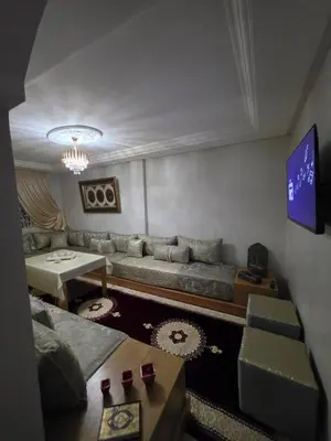 a living room with a couch and a table at Appartement souka fitness in Bouznika