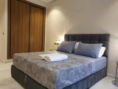 a bedroom with a large bed with blue pillows at Studio Parc Mohammedia in Mohammedia