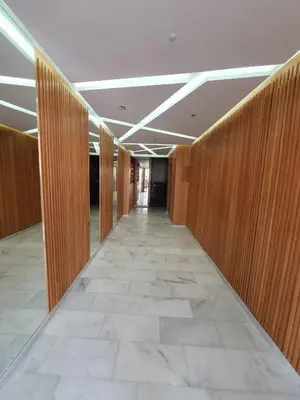 a hallway of an office building with wooden walls and ailed floor at Studio Parc Mohammedia in Mohammedia
