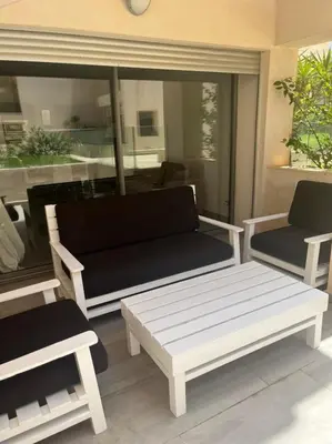 a bench and two chairs on a patio at beach front gardens in Mohammedia