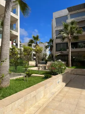 a park in front of a building with palm trees at beach front gardens in Mohammedia