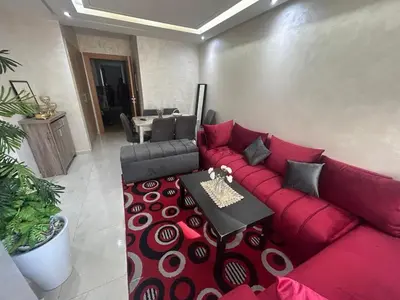 a living room with a red couch and a table at Belle Appt vue sur Piscine à Bouznika plage in Bouznika