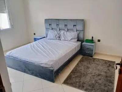 a bedroom with a large bed with a gray headboard at Appartement en bord de mer à Harhoura in Temara