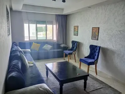 a living room with a couch and two blue chairs at Appartement en bord de mer à Harhoura in Temara