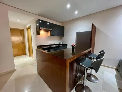 a kitchen with a counter and chairs in a room at Rihla Stays - Anfa City in Casablanca