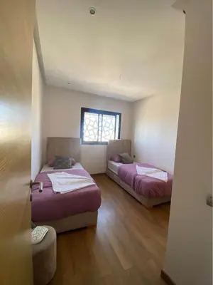two beds in a room with a window at Résidence yassmin in Rabat