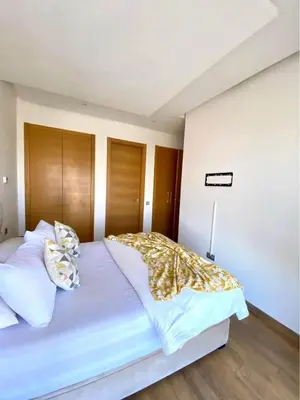 a bedroom with a large bed with white sheets and pillows at Résidence yassmin in Rabat