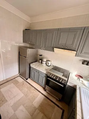 a kitchen with gray cabinets and a stainless steel refrigerator at Luxury Apartment Ocean View and Private Beach Ain Diab in Casablanca