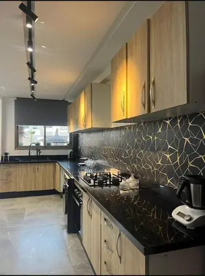 a kitchen with wooden cabinets and a black counter top at Sunset Malaga beach house in Mansouria
