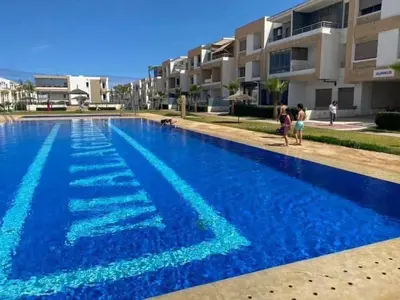 a swimming pool with blue water in front of a building at Sunset Malaga beach house in Mansouria