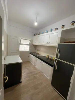 a kitchen with white cabinets and a black refrigerator at Cozy Condo in Rabat in Rabat