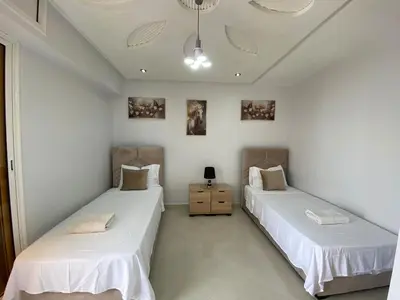 two beds in a room with white walls at Duplex - Pool and Beach in Dar Hamida