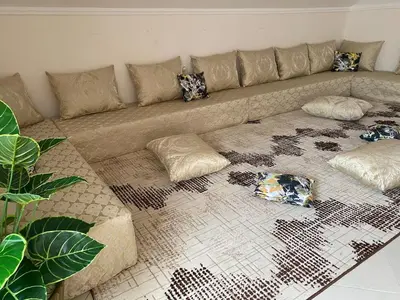 a living room with a couch with pillows on the floor at Duplex - Pool and Beach in Dar Hamida