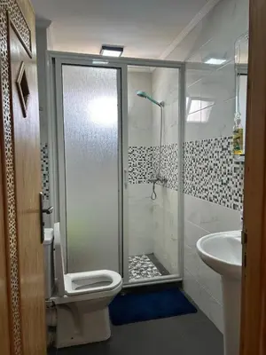 a bathroom with a shower and a toilet and a sink at Duplex - Pool and Beach in Dar Hamida