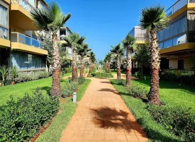 a pathway with palm trees in front of a building at Blue beach in Bir Jedíd Saint-Hubert