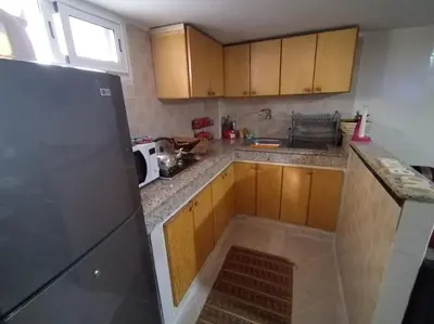 a kitchen with wooden cabinets and a black refrigerator at Studio with Swimmingpool in Harhoura in Temara