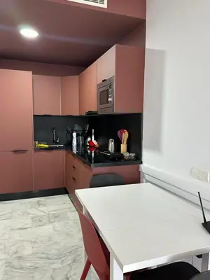 a kitchen with pink walls and a white table and chairs at Charming Studio in Oasis in Oulad Akkou