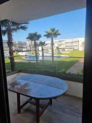 a table in front of a window with palm trees at Appartement Confortable à Tamaris Piscine, Jacuzzi, Proche de la Mer in Tamaris