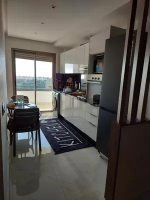 a kitchen with a table and a refrigerator at اجمل شقة in Temara