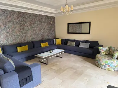 a living room with a blue couch and a table at Savannah beach in Dar Hamida