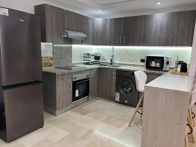 a kitchen with a refrigerator and a dishwasher at Magnifique appartement 2 chambres vue sur piscine - Sidi Rahal in Sidi Rahal