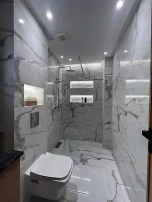 a bathroom with a white toilet and marble walls at Magnifique appartement 2 chambres vue sur piscine - Sidi Rahal in Sidi Rahal