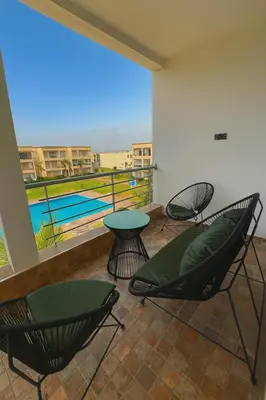 a patio with chairs and a table and a pool at Magnifique appartement 2 chambres vue sur piscine - Sidi Rahal in Sidi Rahal