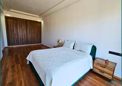 a bedroom with a white bed and a wooden floor at Le Refuge Océanique idéal ! in O Ben Slimane