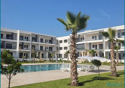 a large apartment building with a swimming pool and palm trees at Le Refuge Océanique idéal ! in O Ben Slimane