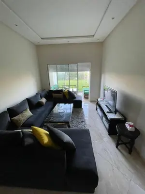 a living room with a black couch and a flat screen tv at Appartement casa bay sidi rahel in Sidi Rahal