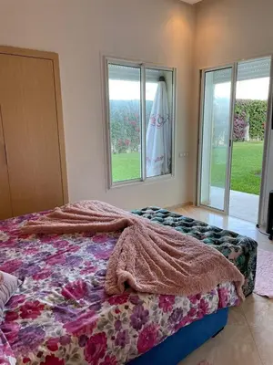 a bedroom with a bed with a blanket and windows at Appartement casa bay sidi rahel in Sidi Rahal