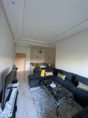 a living room with a blue couch and a guitar at Appartement casa bay sidi rahel in Sidi Rahal