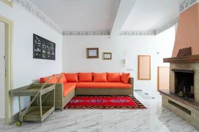 an orange couch in a white room with a fireplace at Coastal Moroccan Retreat with Ocean Views in Rabat