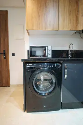 a washing machine in a kitchen with a microwave at Central and Chic Apartment in the Heart of Casablanca Near To Station Tramway Abdelmoumen in Casablanca