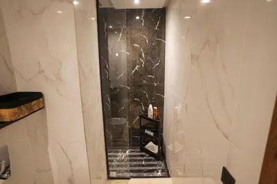 a bathroom with a shower with a black marble wall at Central and Chic Apartment in the Heart of Casablanca Near To Station Tramway Abdelmoumen in Casablanca