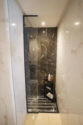 a bathroom with a shower with a black marble wall at Central and Chic Apartment in the Heart of Casablanca Near To Station Tramway Abdelmoumen in Casablanca