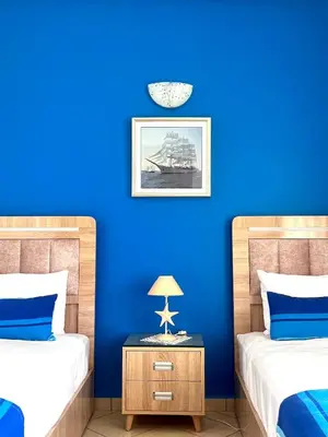 a blue room with two beds and a table with a lamp at Villa près de la mer, sidi rahal route de dar bouazza in Bir Jedíd Saint-Hubert