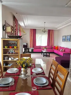 a living room with a table and chairs and a couch at Villa près de la mer, sidi rahal route de dar bouazza in Bir Jedíd Saint-Hubert